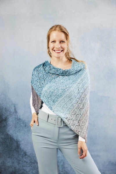 DIY-Strickschal in blau-grauen Farbverlauf, feines Muster; kombiniert mit eleganter hellgrauer Hose, modisch.