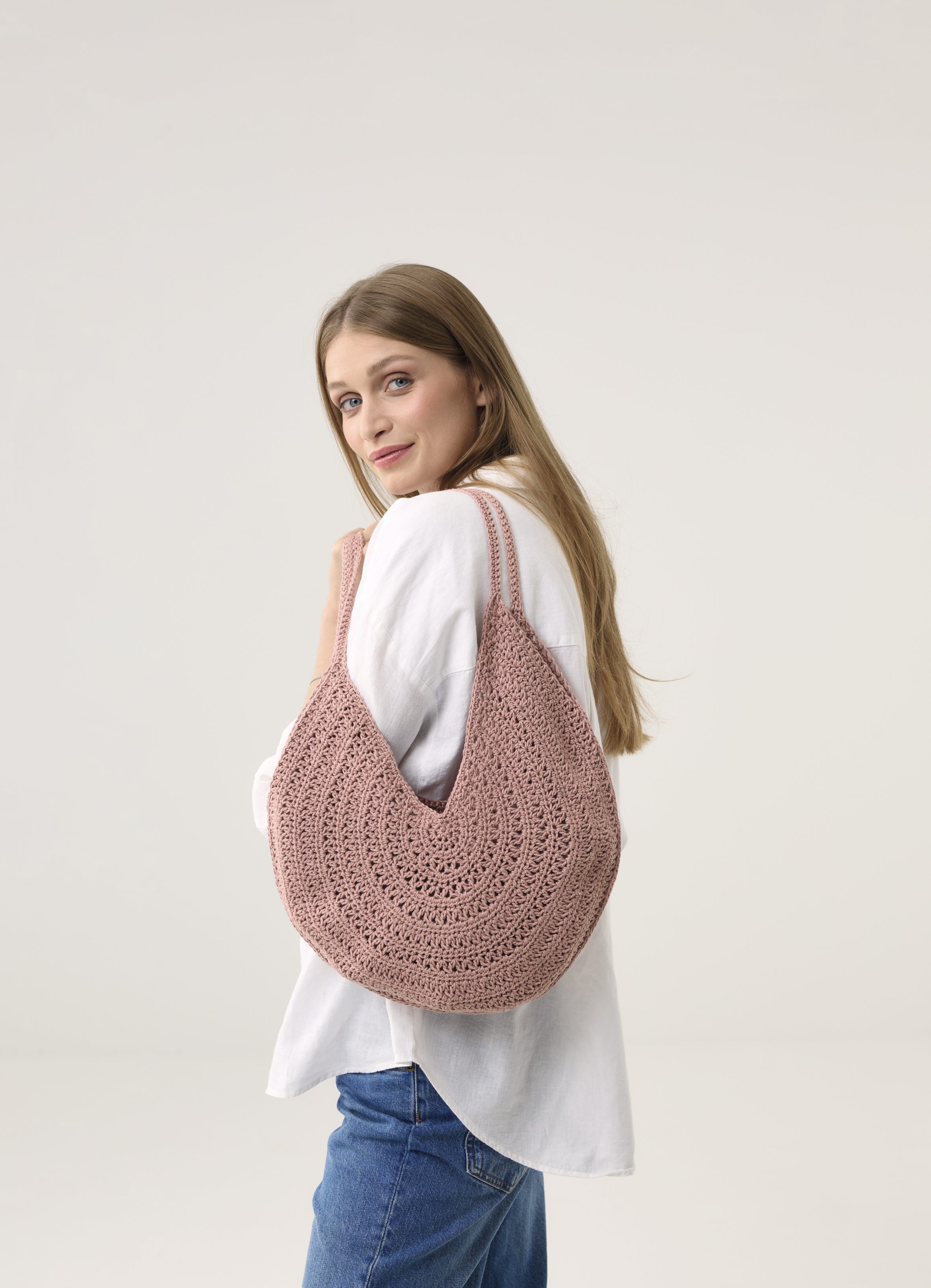 Rosa, gehäkelte Tasche, handgemacht; lässiger Stil, kombiniert mit weißem Oberteil und blauer Jeans.