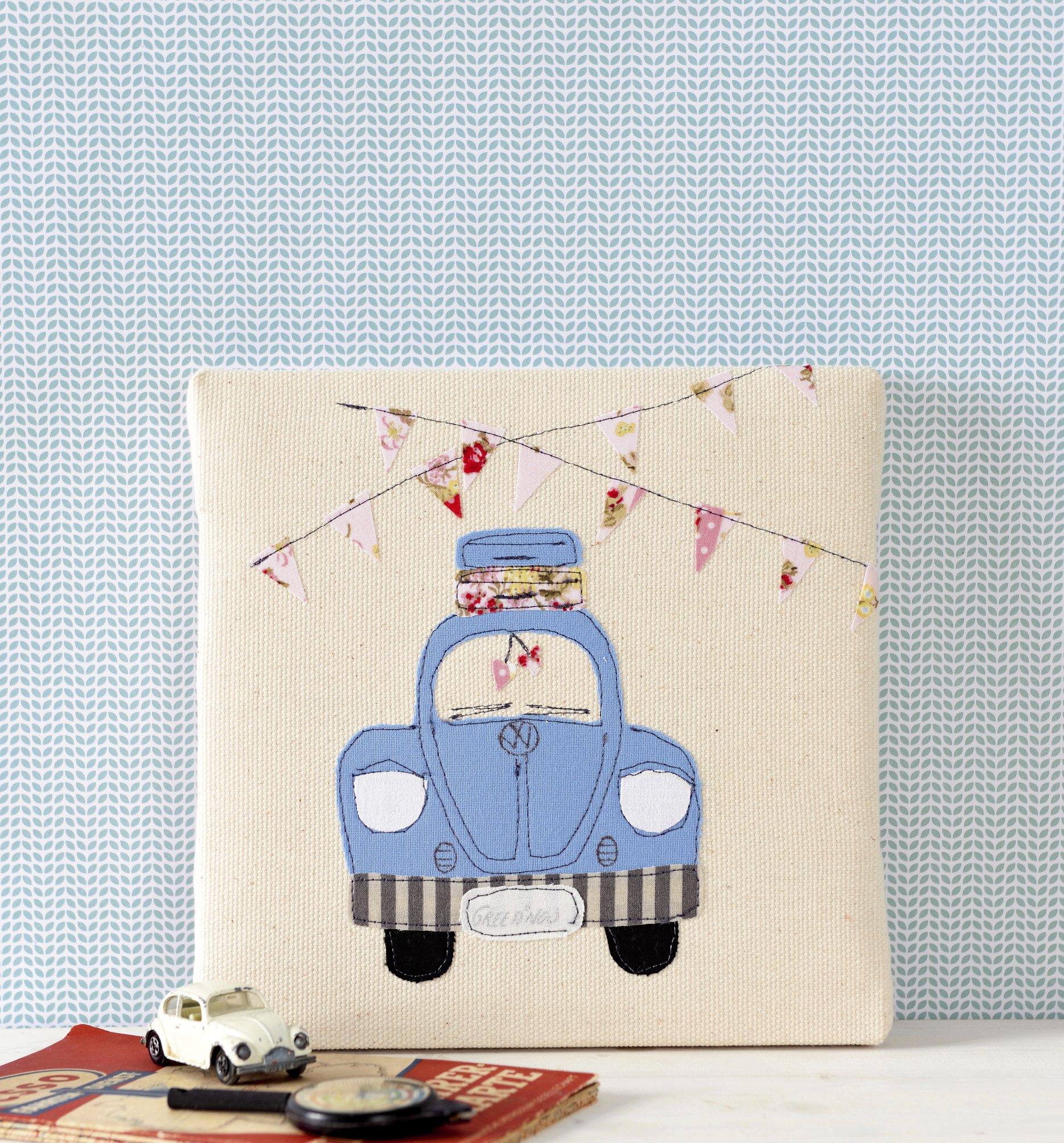 Beiger Leinwandbezug mit blauem Auto, handgemachtem Patchwork. Bunte Wimpel oben, modisch und DIY.