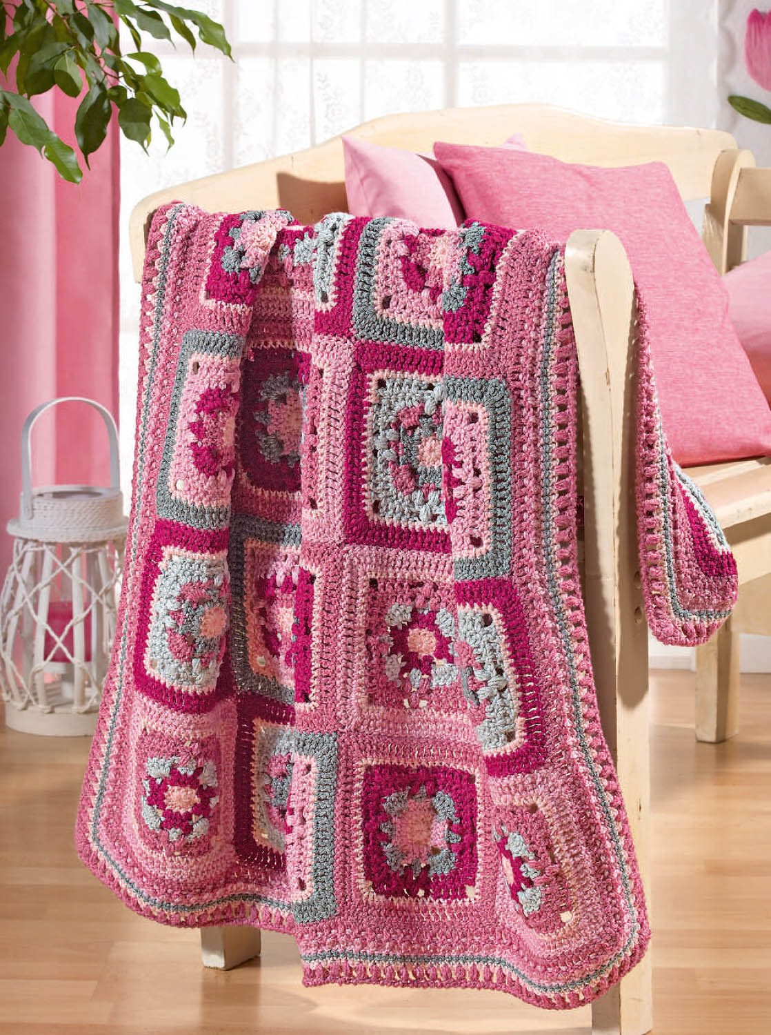 Farbenfrohe, handgemachte Häkeldecke in Rosa und Grau mit quadratischem Blumenmuster; modisch und kreativ.