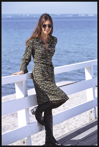 Modisches Kleid in Grün mit geometrischem Muster, taillierter Schnitt, kombiniert mit schwarzen Stiefeln.