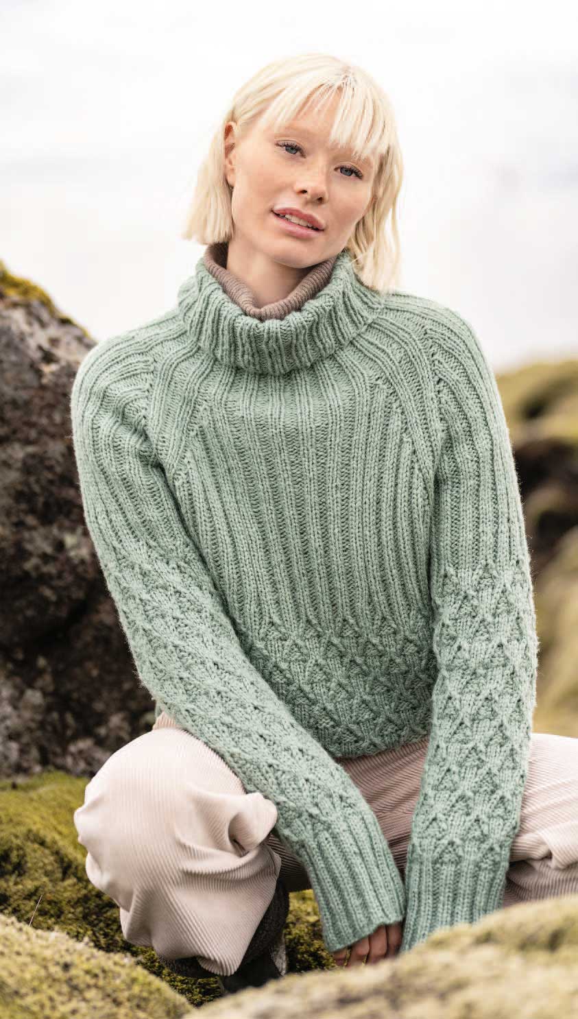 Mintgrüner Rollkragenpullover, handgestrickt, Zopfmuster, modisch, kombiniert mit beigen Hosen.
