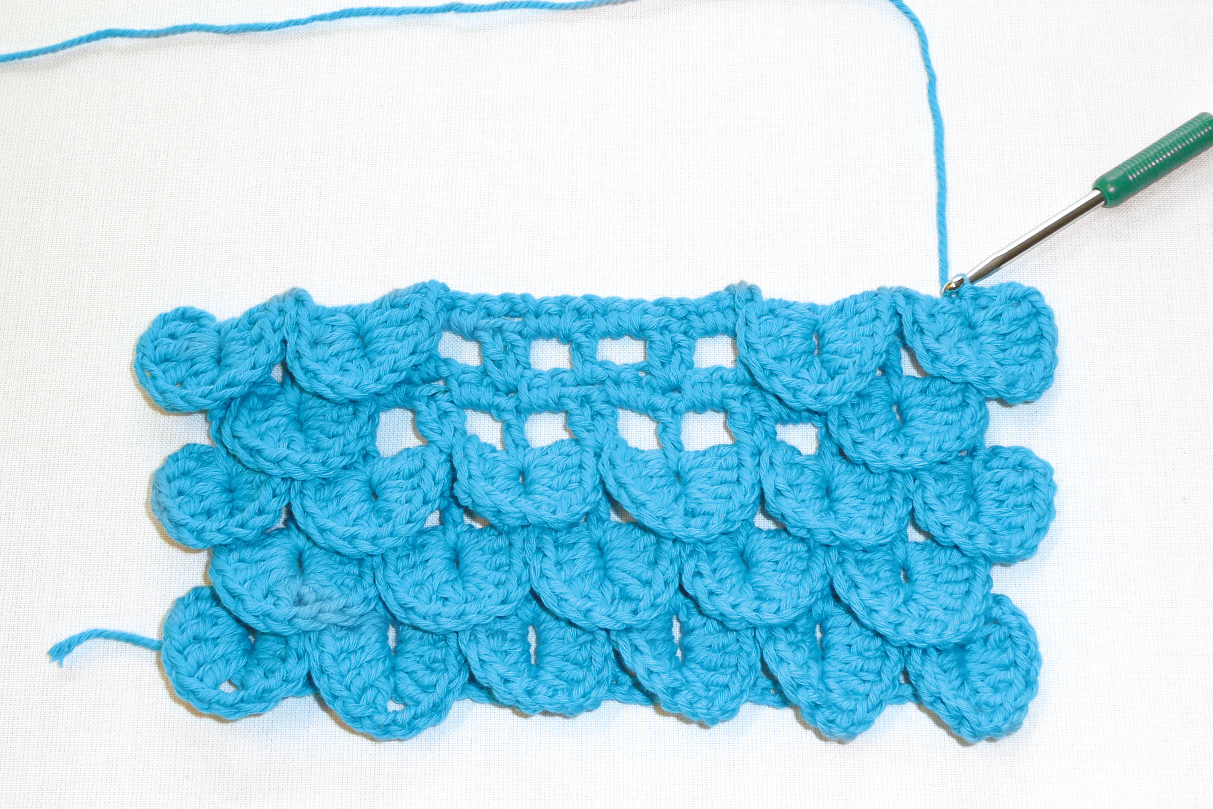 Blaue Häkelarbeit mit Schuppenmuster, modisch und handgemacht, zeigt künstlerisches DIY-Handarbeitstalent.