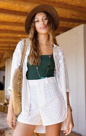 Weißes Häkelhemd über grüner Top, weißer Shorts, Strohhut. Modisch, handgemacht, sommerlich, Boho-Vibes.