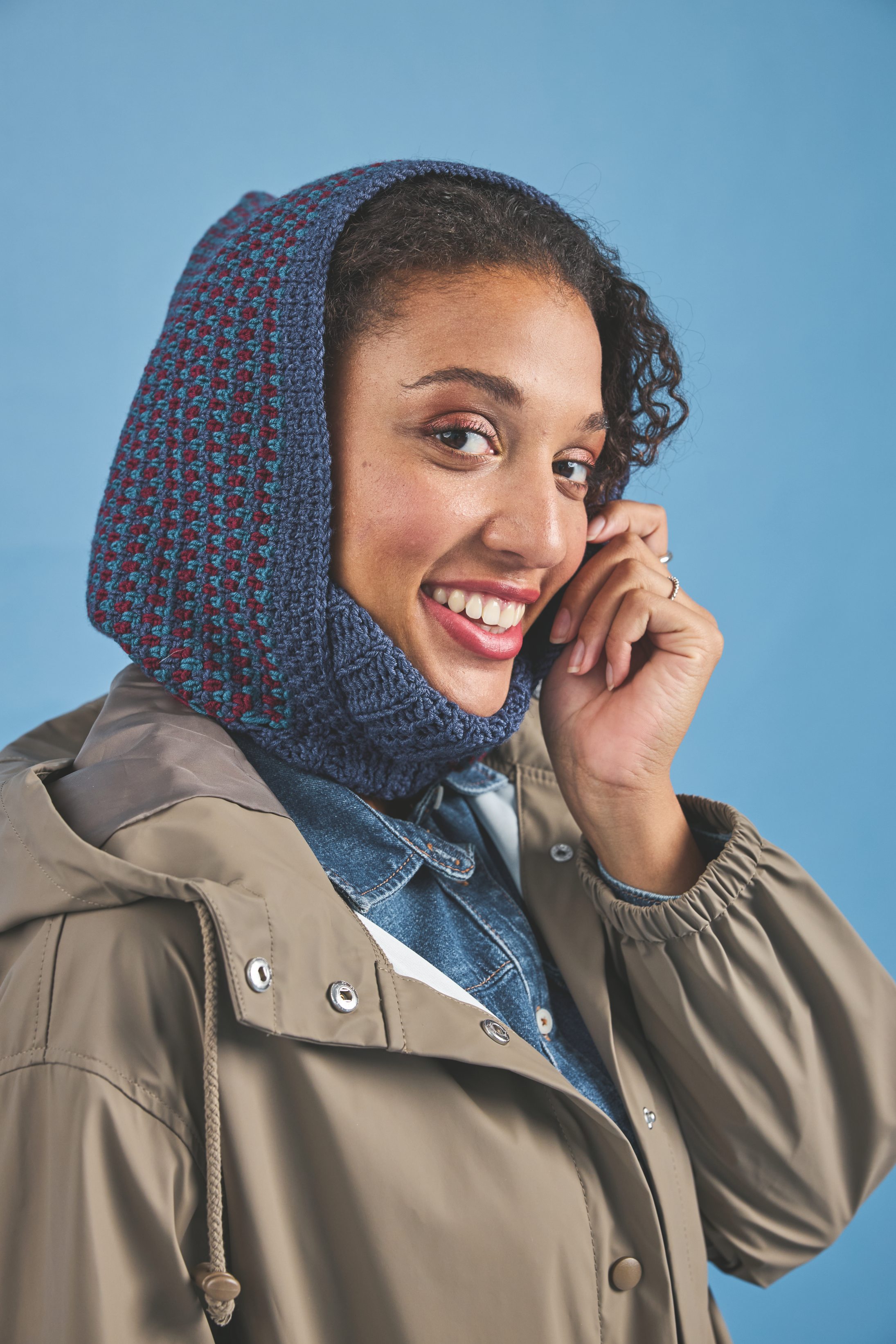 Handgemachter, gemusterter blau-roter Strickhaube, beige Jacke. Modisch, trendy, DIY, stilvoll.