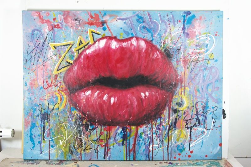 Riesenrote Lippen auf blauem Hintergrund, gespickt mit bunter Street-Art. Farbspritzer und Graffiti-Elemente.