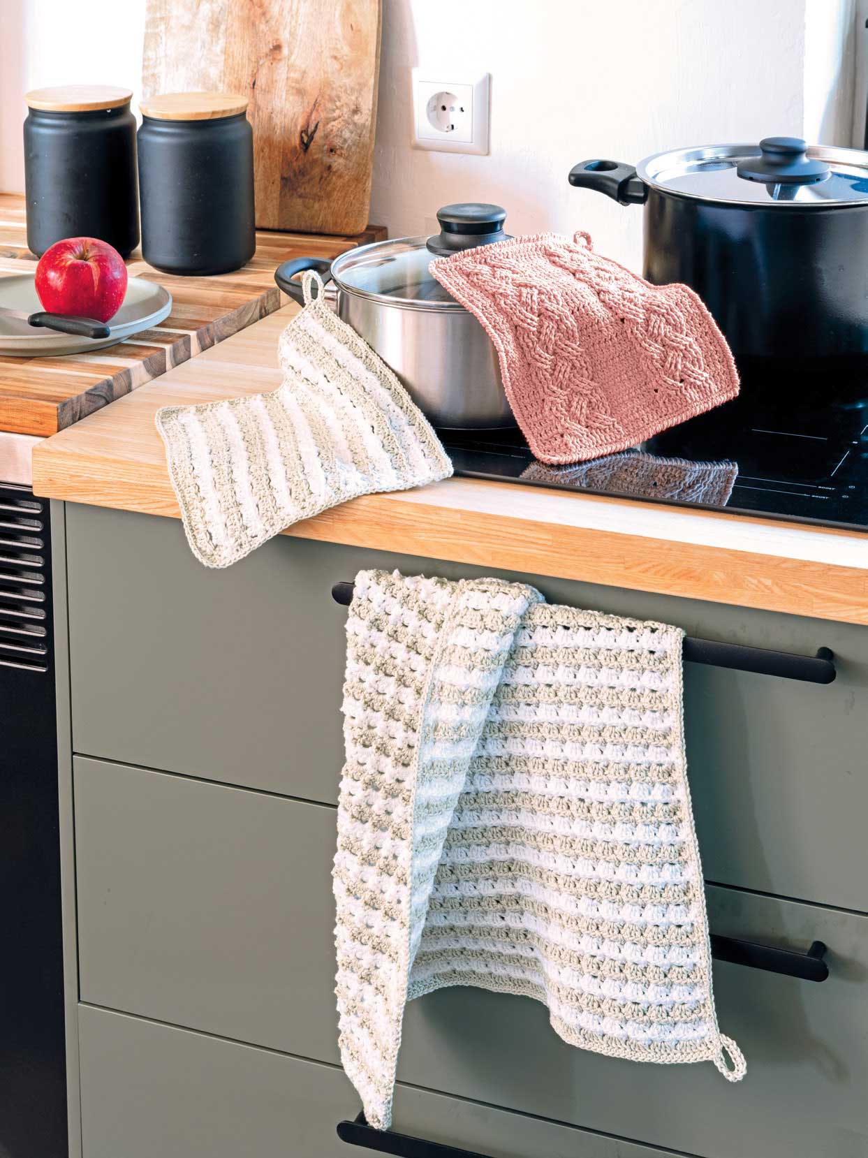 Gestrickte Topflappen in Rosa und Creme, handgemacht, mit Streifen- und Zopfmuster, stilvoll und funktional.