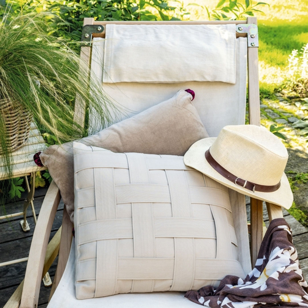 Beige Kissen mit Flechtmuster, cremefarbener Hut, braun gemusterter Schal. Modisch, handgefertigt, zeitlos.