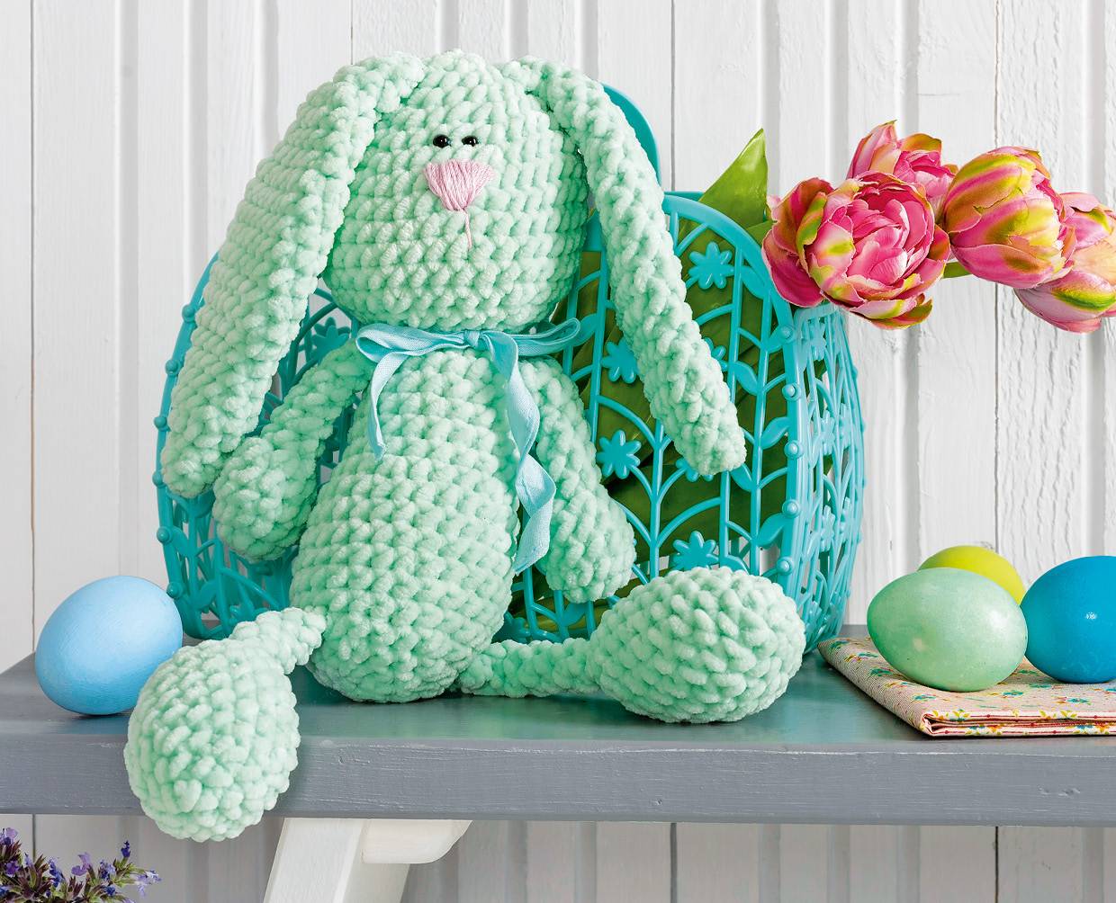 Mintgrüner Hase, grob gehäkelt, DIY-Stil, blaues Satinband. Handgemachte, strukturierte Oberfläche.
