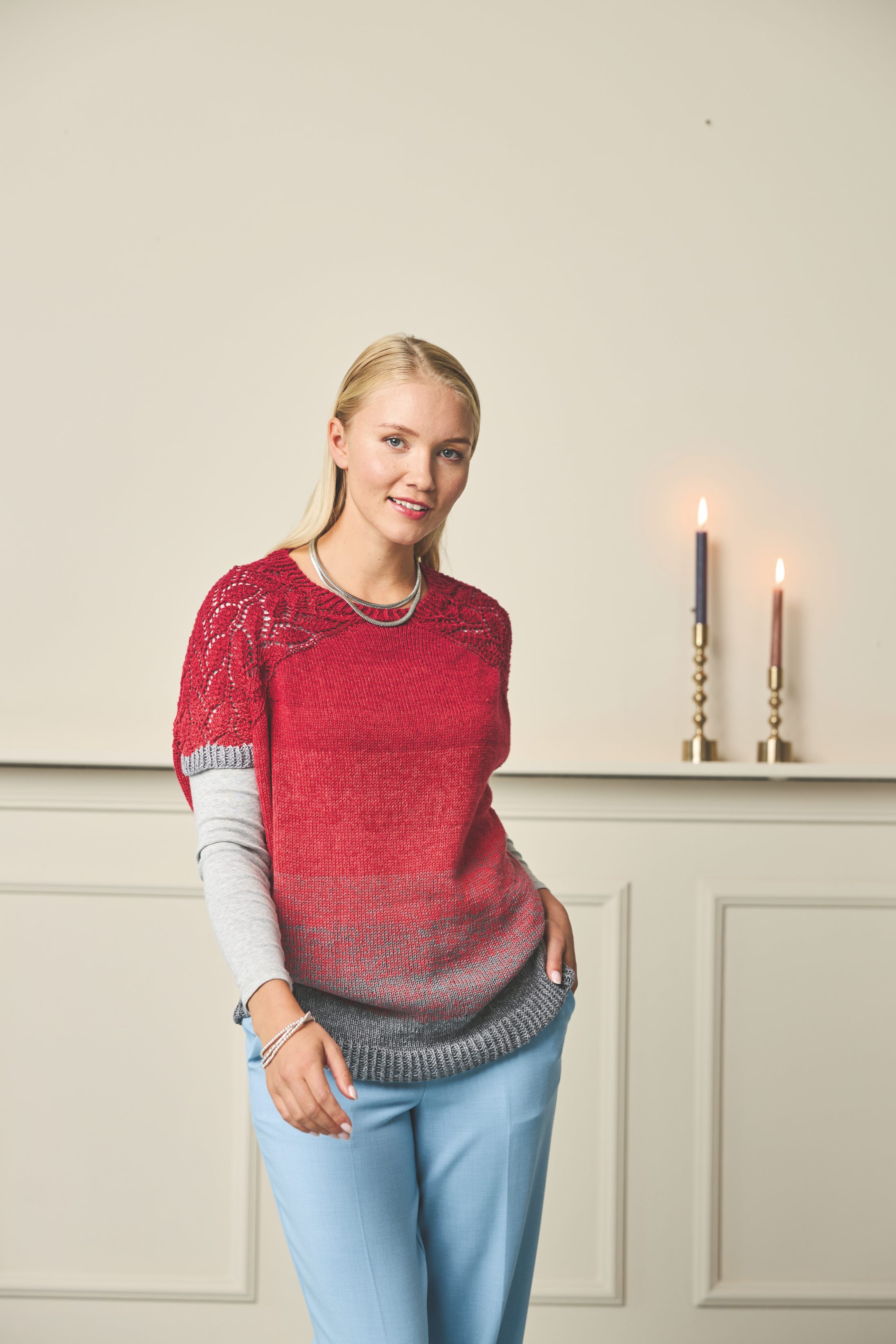 Modischer, handgemachter Pullover in Rot-Grau-Verlauf, luftige Spitze, kombiniert mit pastellblauer Hose.