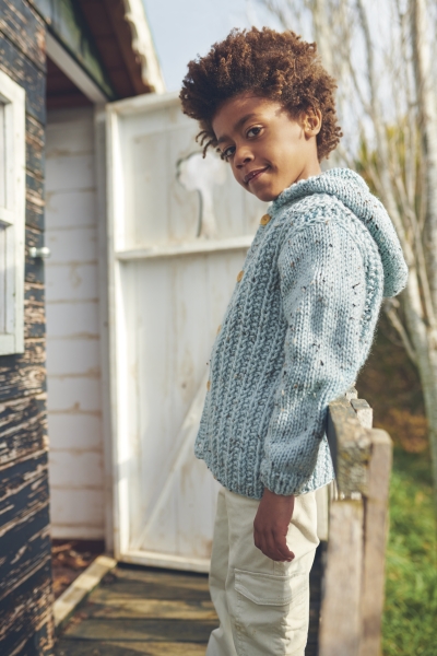 Hellblauer, selbstgemachter Strickpullover mit Kapuze, grobes Muster, kombiniert mit beigefarbener Hose.