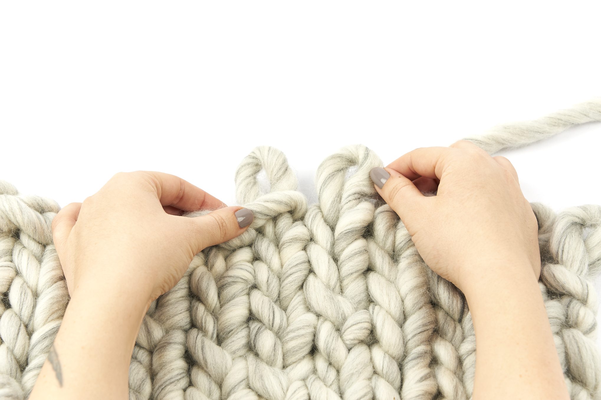 Handgemachtes, dickes Strickwerk aus grauem Garn mit großen Maschen. Modisch, DIY, kunstvoll.