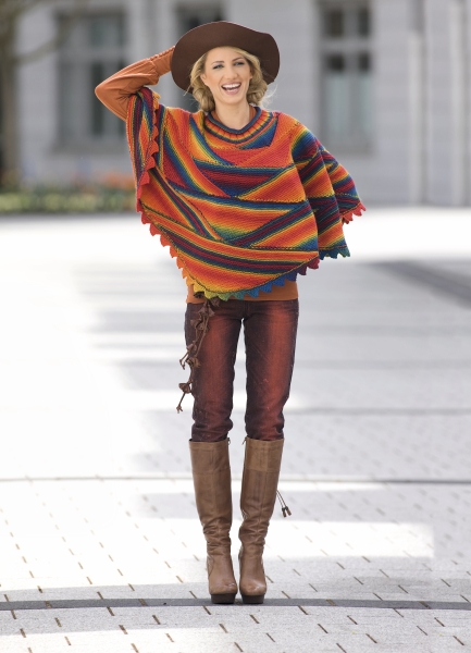 Modischer, handgefertigter Poncho mit Regenbogenstreifen, kombiniert mit braunen Stiefeln und enger Jeans. Boho-Chic.