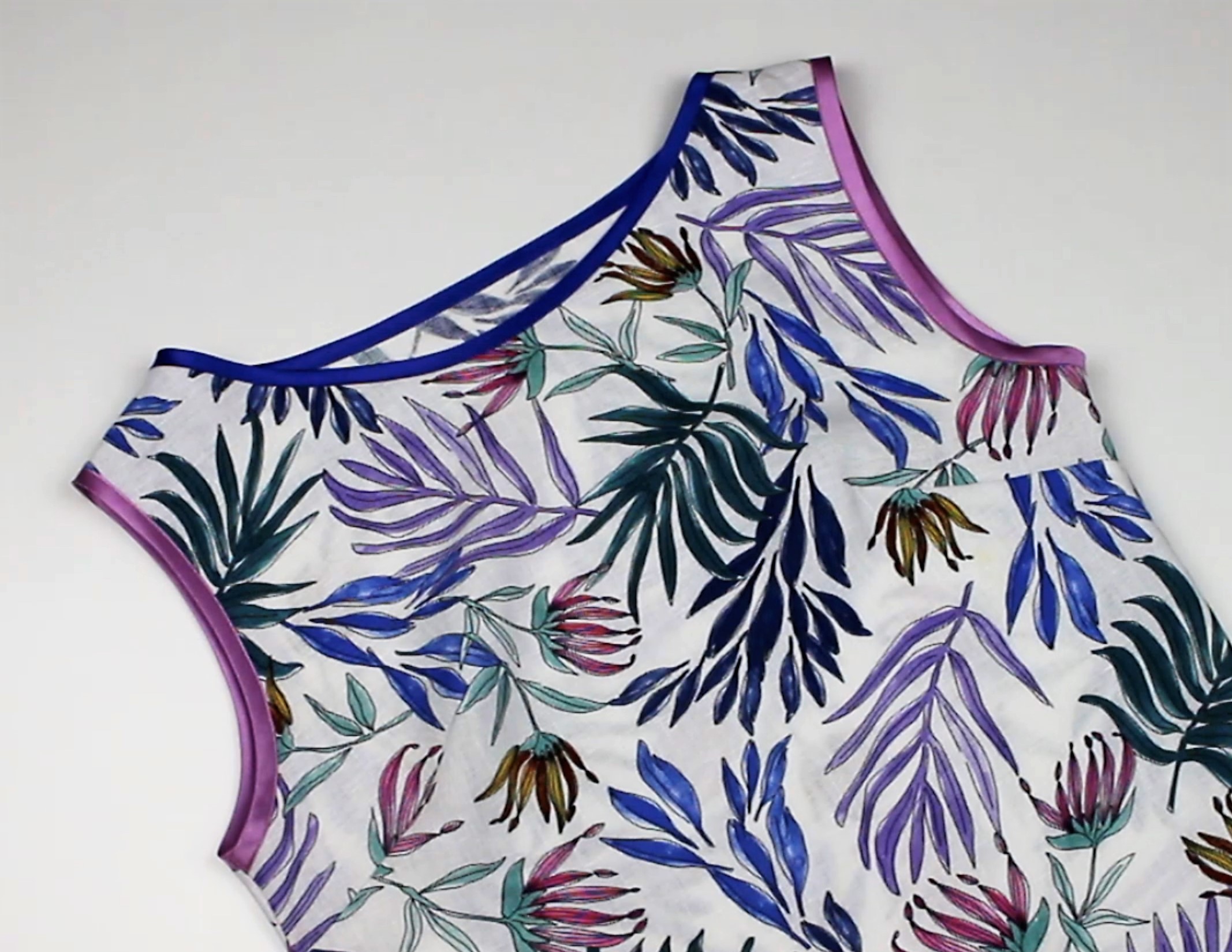 Asymmetrisches Top mit buntem Blumenmuster, rosa und blaue Ränder, handgemacht, sommerlich und stilvoll.