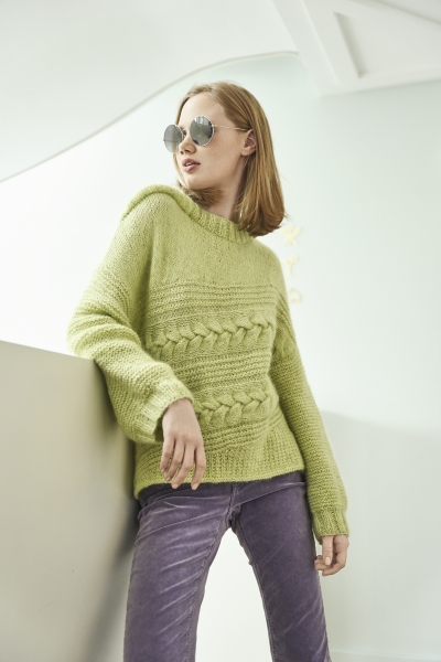 Grüner Strickpullover mit Zopf- und Strukturmuster, modisch kombiniert mit violetten Cordhosen. Handarbeit.
