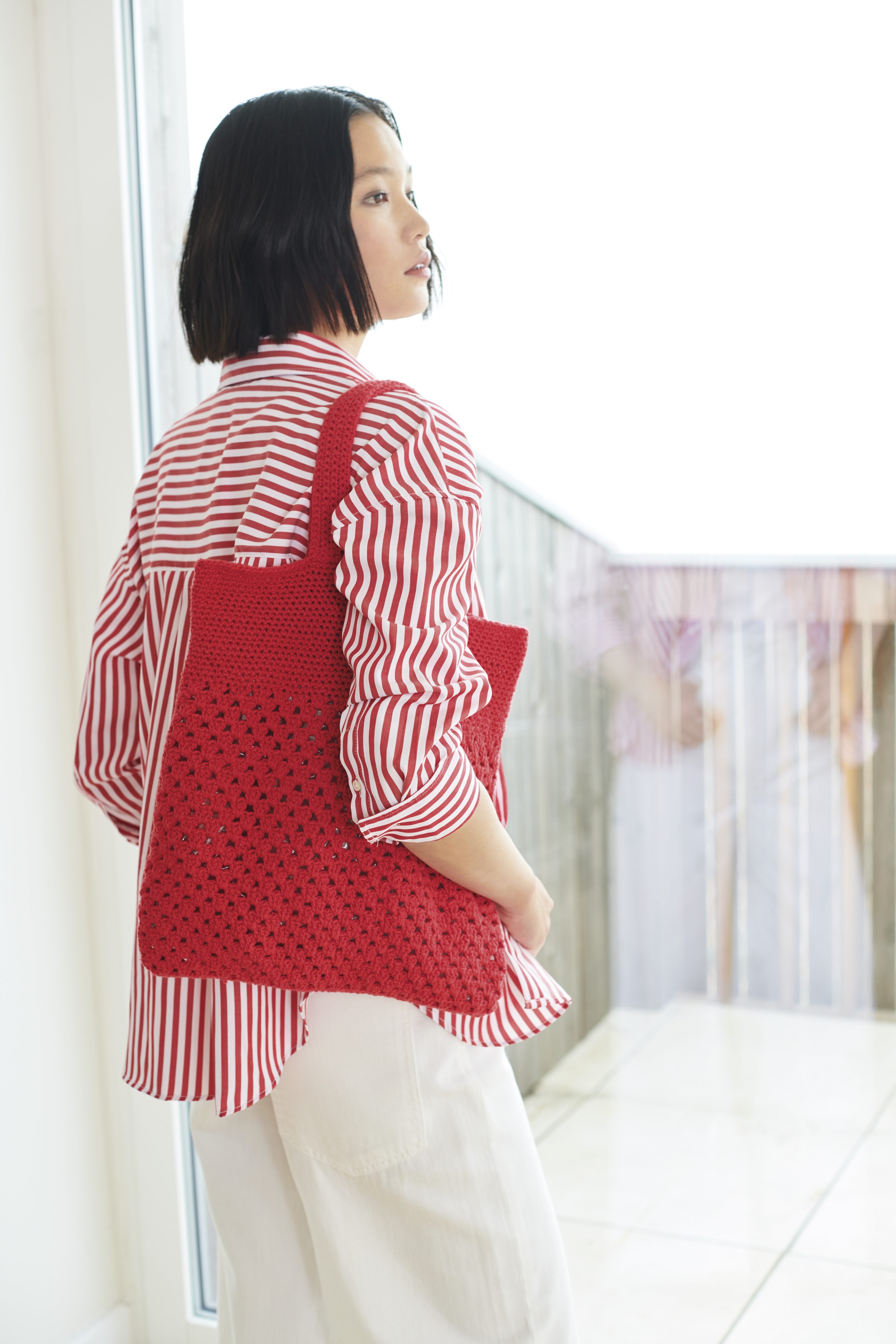 Modisches rot-weiß gestreiftes Hemd, kombiniert mit handgemachter roter Stricktasche. Elegante und stilvolle Kombination.