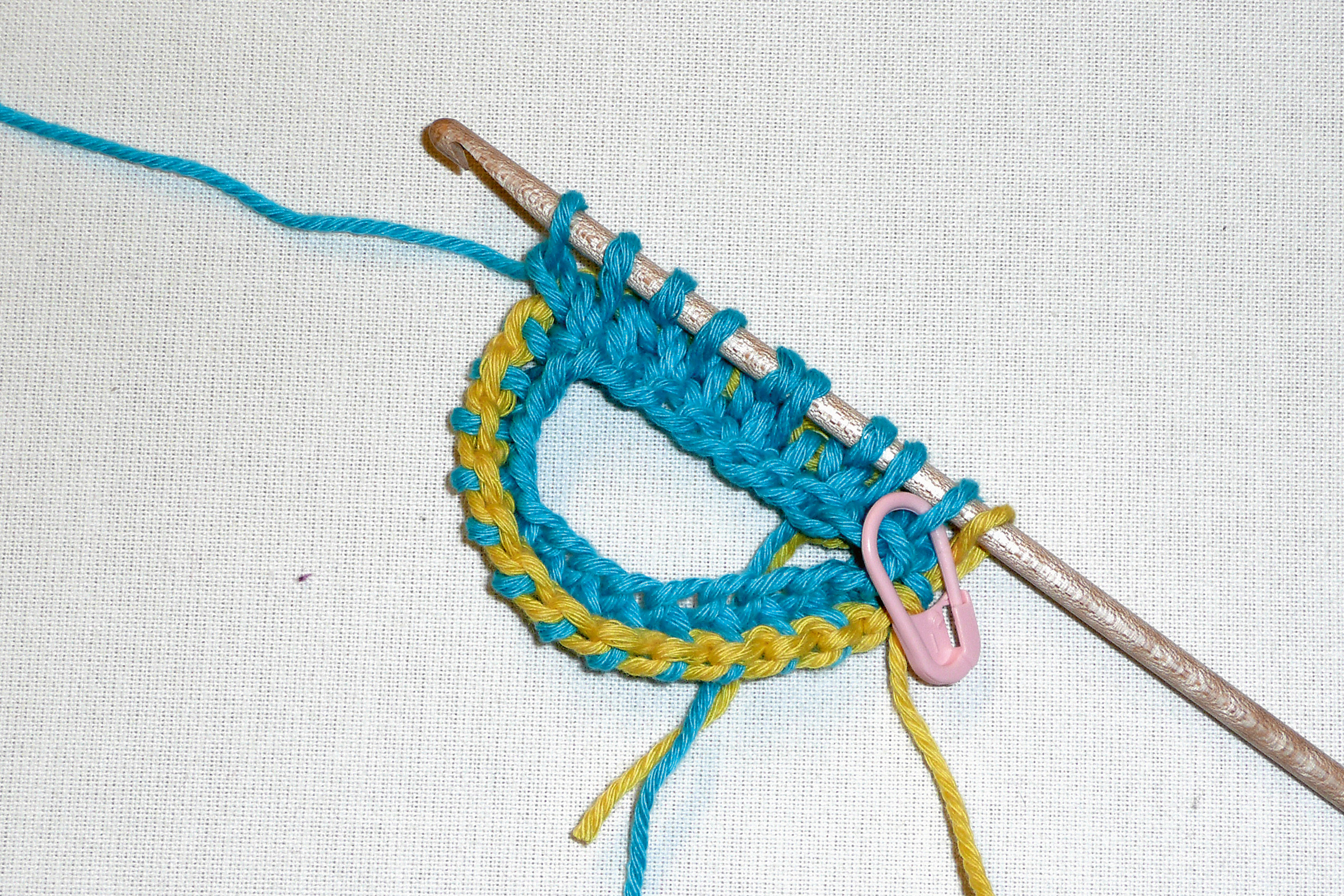 Blau-gelbes DIY-Strickmuster mit Häkelnadel und Maschenmarker, handgemacht, modisch.