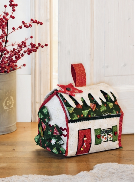 DIY-Patchwork-Tasche in Hausform, farbenfroh gemustert, mit roten Akzenten und winterlichen Motiven.