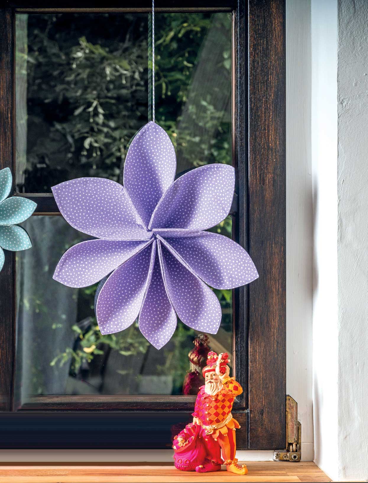 Lila Stoffblume mit weißen Punkten, handgemacht, DIY, gefaltet, hängend am Fenster.