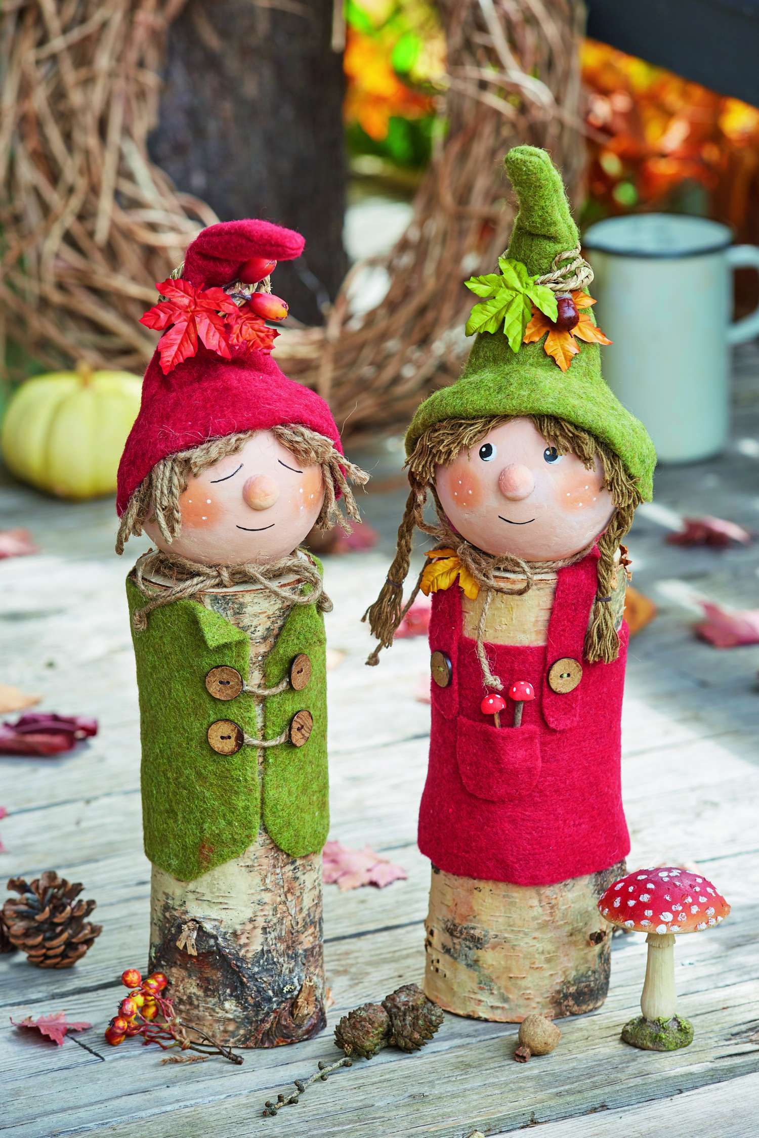 Handgemachte Figuren in Rot und Grün mit Filzmänteln, Knöpfen und bunten Hüten, rustikaler DIY-Stil.