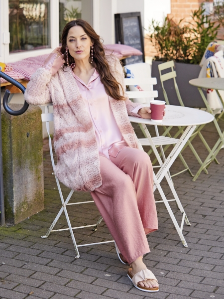 Modisch: Rosa Strickjacke mit Streifenmuster, fließende Seidenbluse, weite Stoffhose. DIY-Charme mit handgemachten Details.