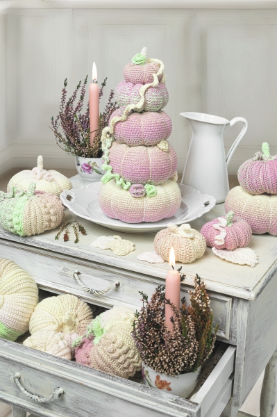 Pastellfarbene, gehäkelte Kürbisse in sanften Rosa- und Cremetönen. Textur: kuschelig, kunstvoll, handgemacht.