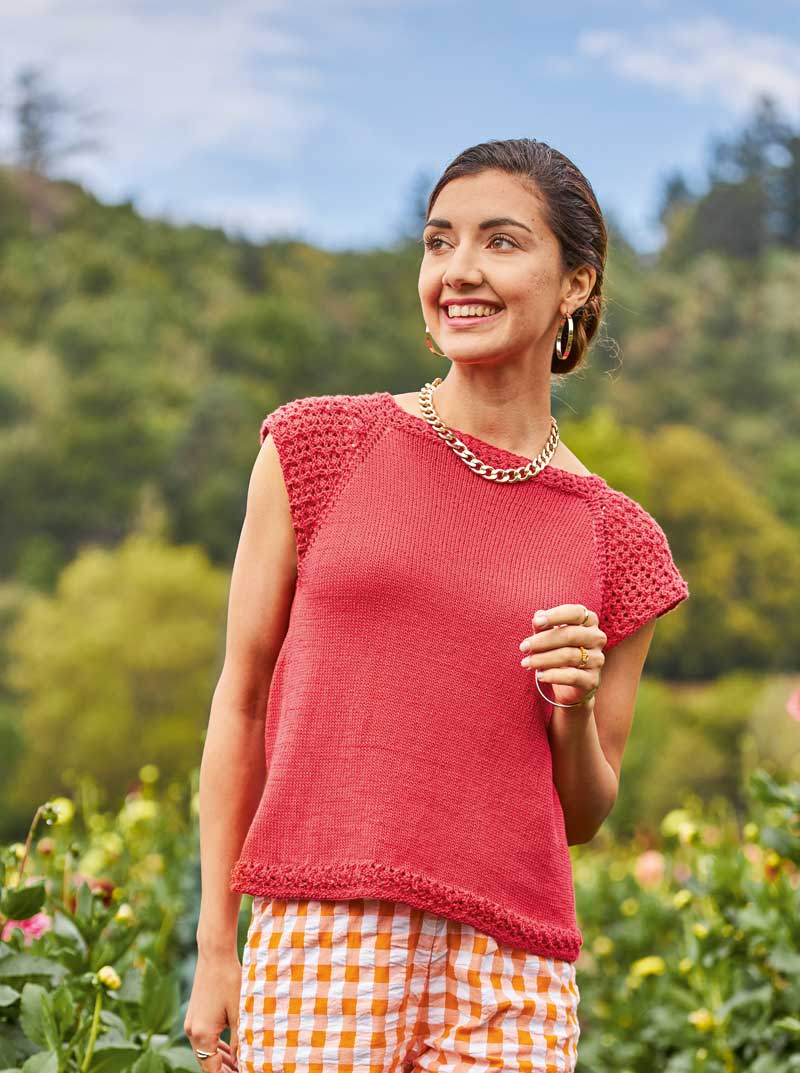 Rotes, handgemachtes Top mit gehäkelten Ärmeln, kombiniert mit modischer karierter Shorts.