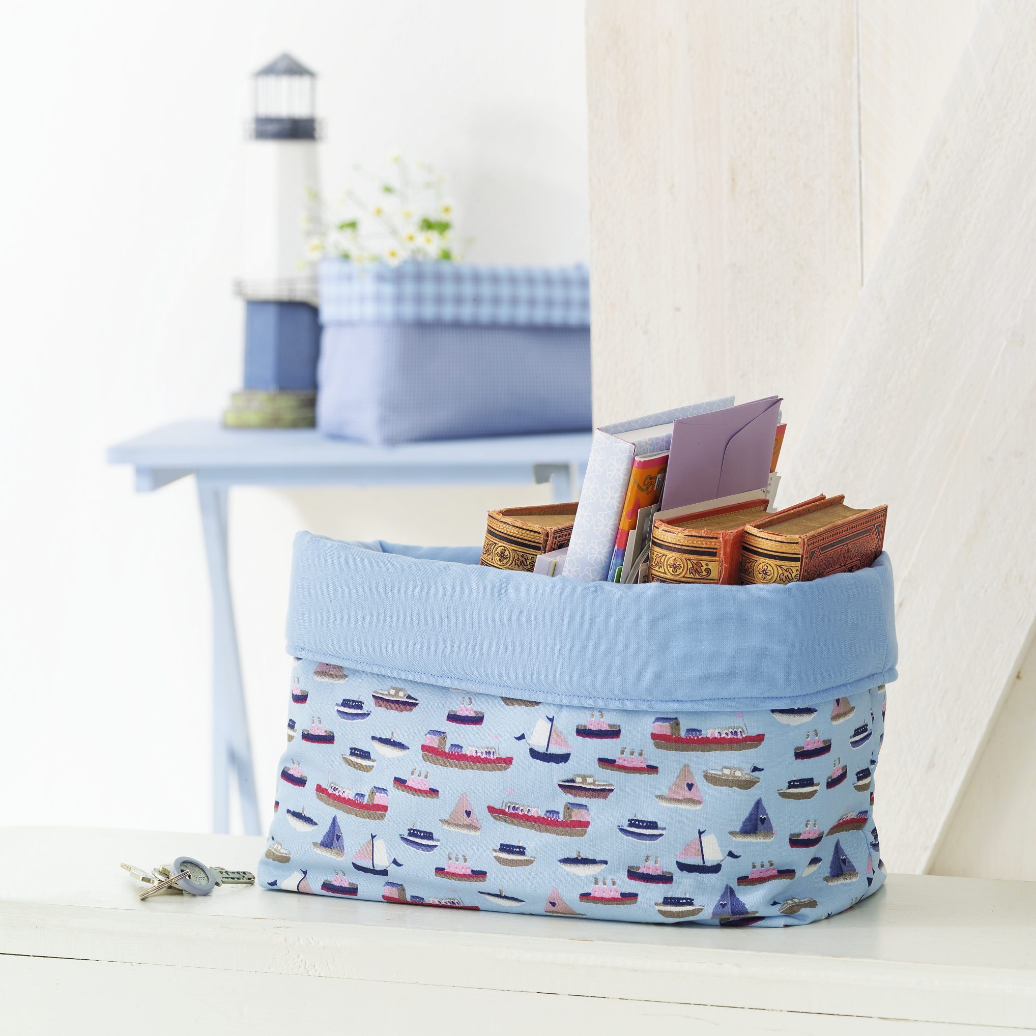 Hellblauer Korb mit buntem Bootsmuster, handgemacht. Kreative DIY-Dekoration, idealer maritimer Akzent.