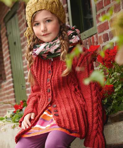 Roter Zopfmuster-Cardigan, gelbe Strickmütze, bunte Streifenkleid, farbenfroher Schal. Modisch, handgemacht.