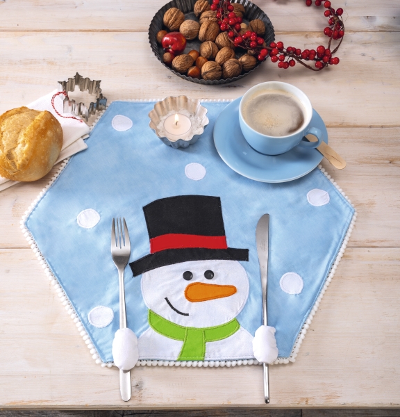 Helles, selbstgemachtes Tischset mit Schneemannmotiv; blau-weiße Farbpalette, mit verspielten Mustern verziert.