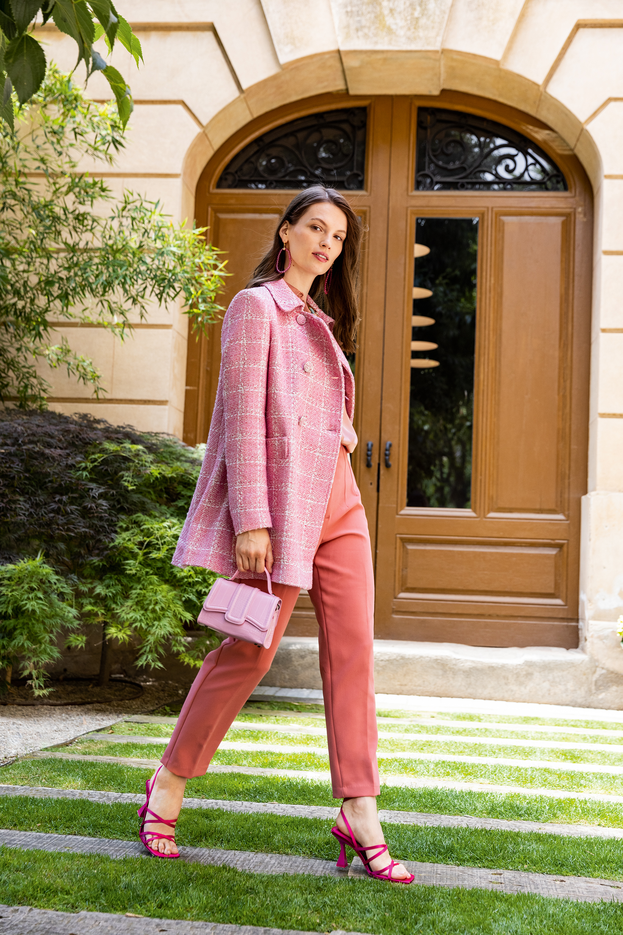 Modischer Mantel in Rosa mit Karomuster, kombiniert mit lachsfarbenen Hosen und passenden Accessoires.