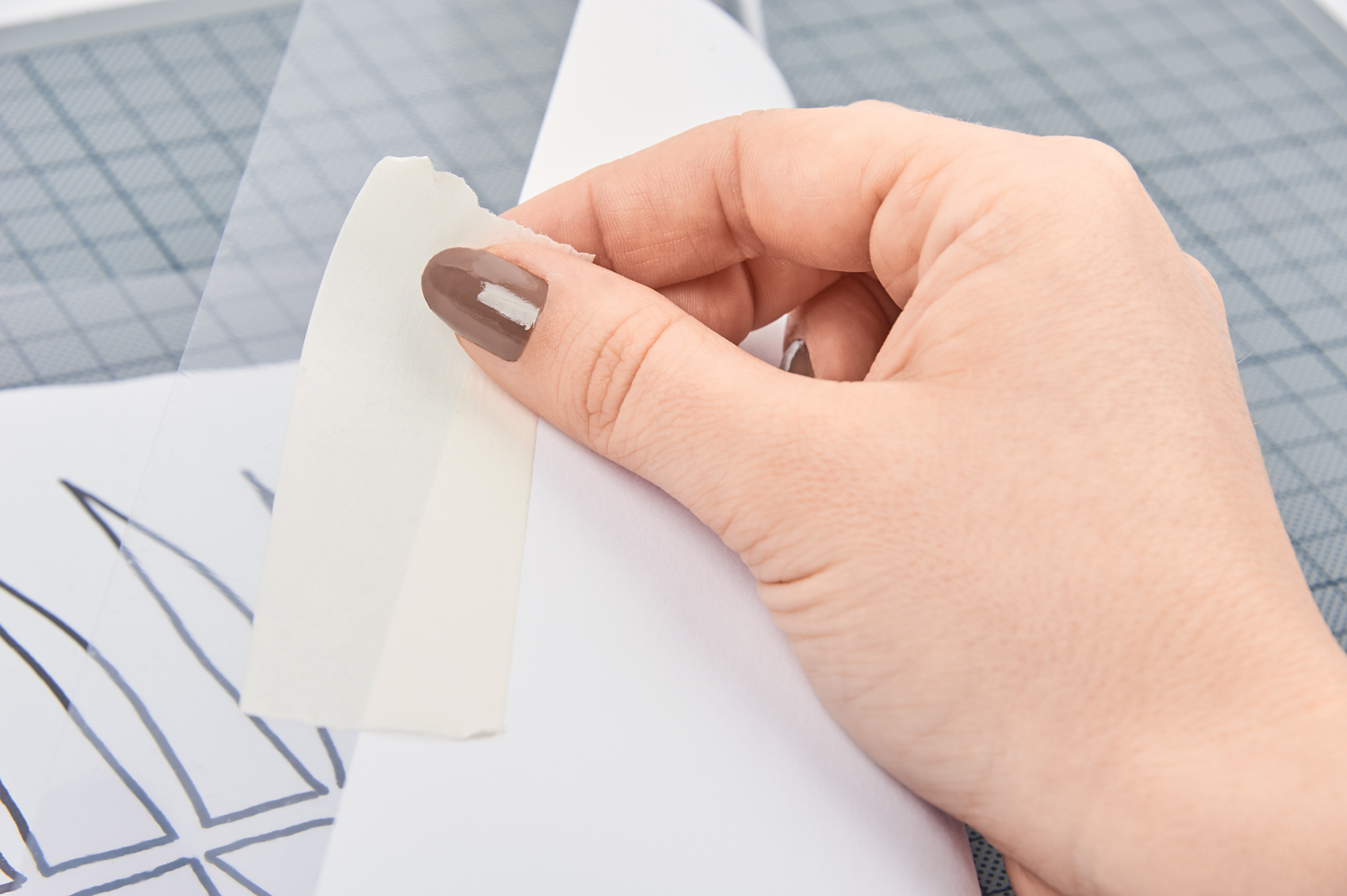 Eine Hand platziert Klebeband präzise auf weißem Papier, ideal für DIY-Projekte.