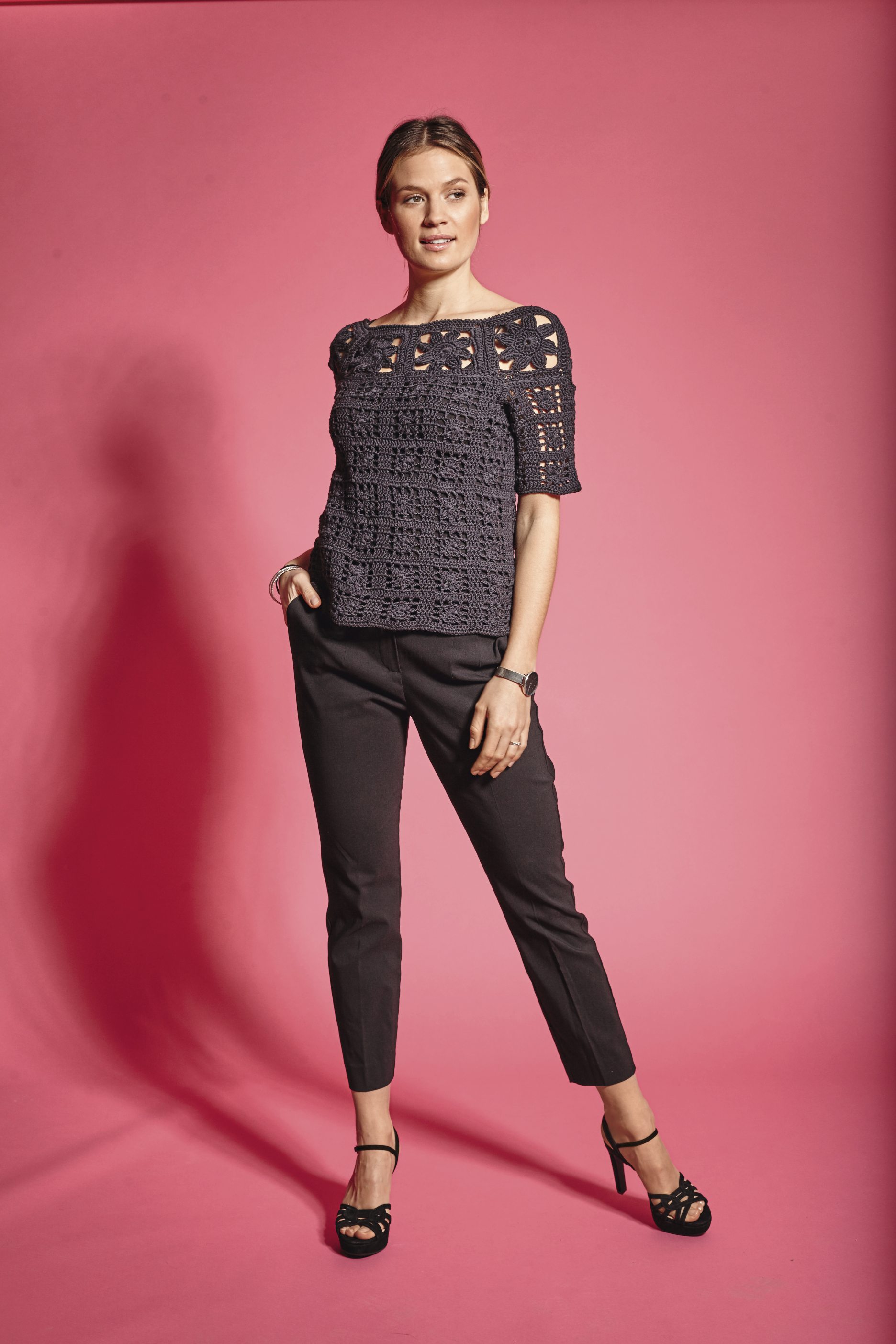 Schwarzes gehäkeltes Top, modisch und handgemacht, kombiniert mit schmal geschnittener Hose und eleganten Sandaletten.