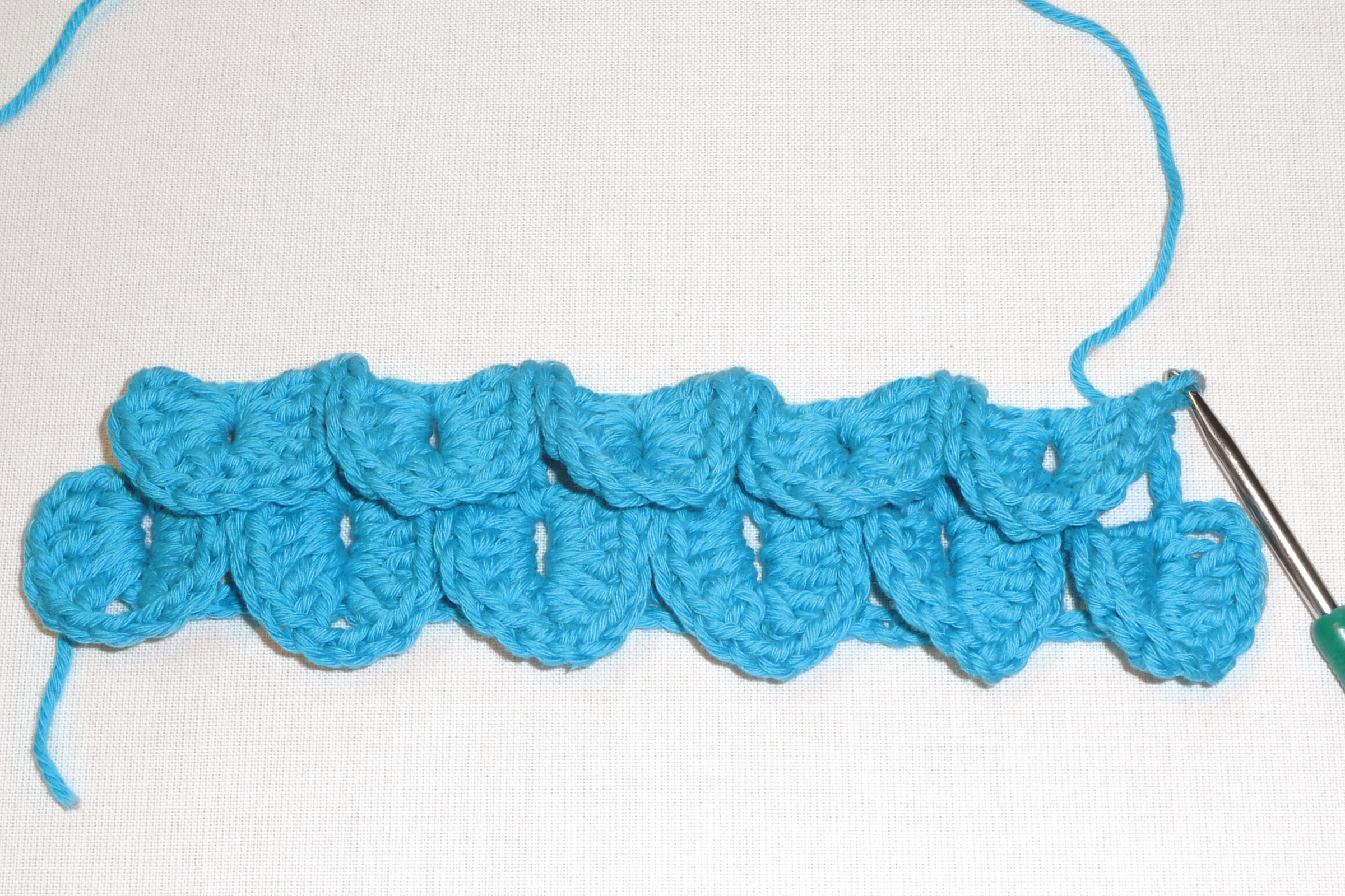 Türkise, handgehäkelte Kreation mit strukturierter Schuppenmusterung. DIY-Kunstwerk.