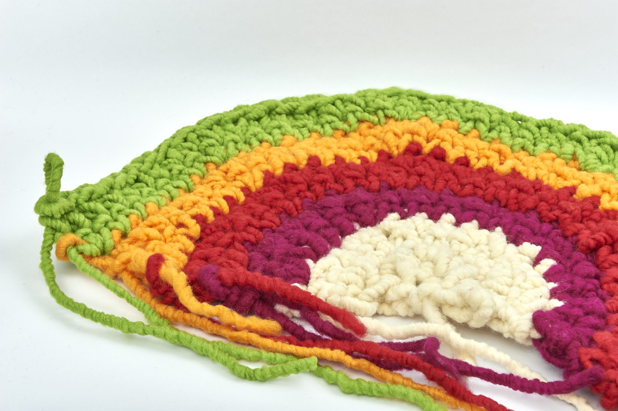 Leuchtende Regenbogenfarben in handgemachtem Häkelmuster. DIY-Charme, grobe Maschen, einzigartige Textur.
