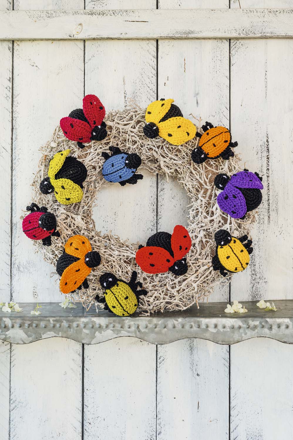 Handgemachter Kranz mit farbenfrohen, gehäkelten Marienkäfern. Detailreiche DIY-Handarbeit, lebendige Farbgestaltung.