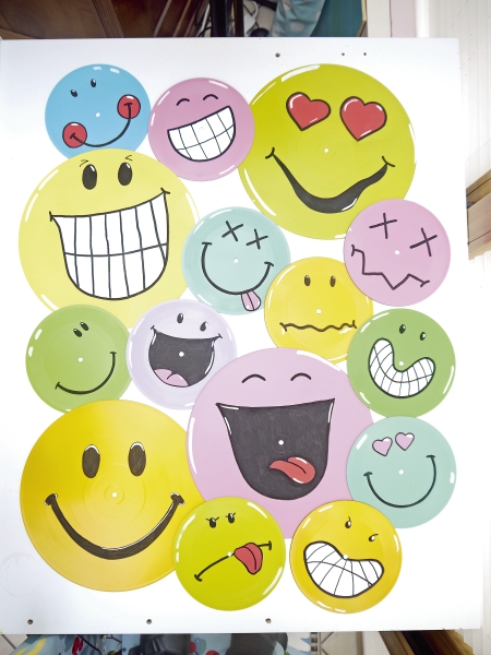 Farbige Schallplatten mit handgemalten Emoji-Motiven, fröhlich und kreativ, DIY-Charme.