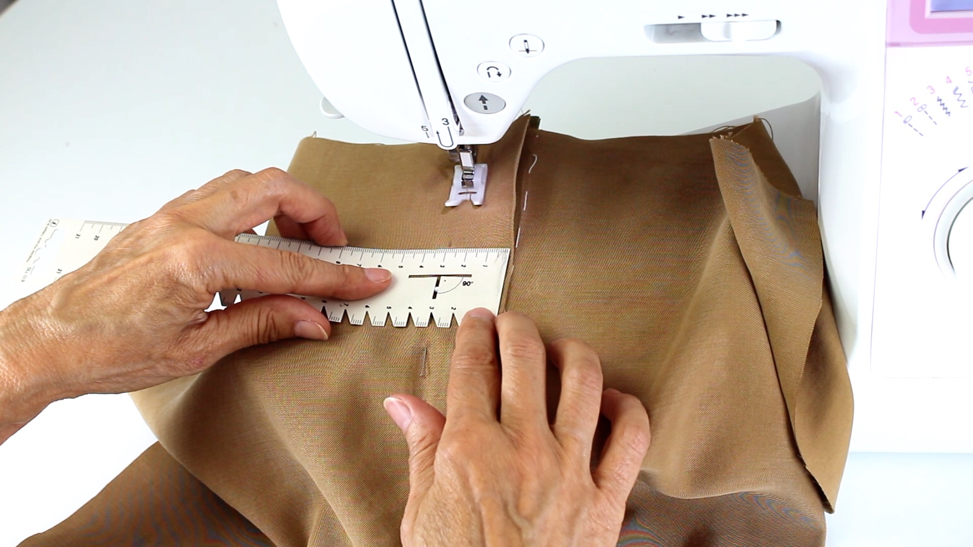 Brauner Stoff, sorgfältig genäht, Maßband, akkurates DIY-Design, modische Präzision.
