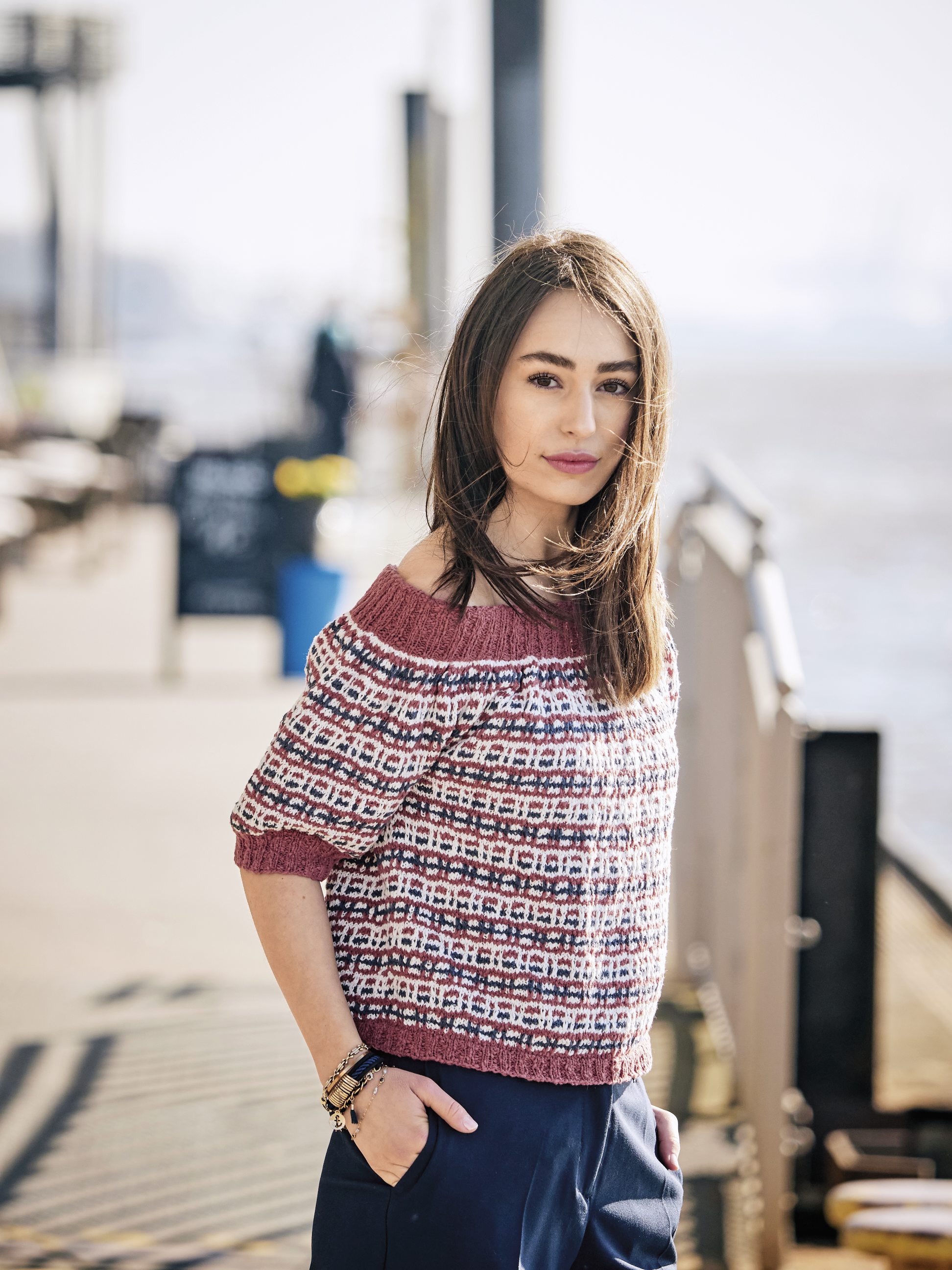Bunter, gestrickter Pullover mit Off-Shoulder-Design, geometrischem Muster, kurze Ärmel, modern und trendig.