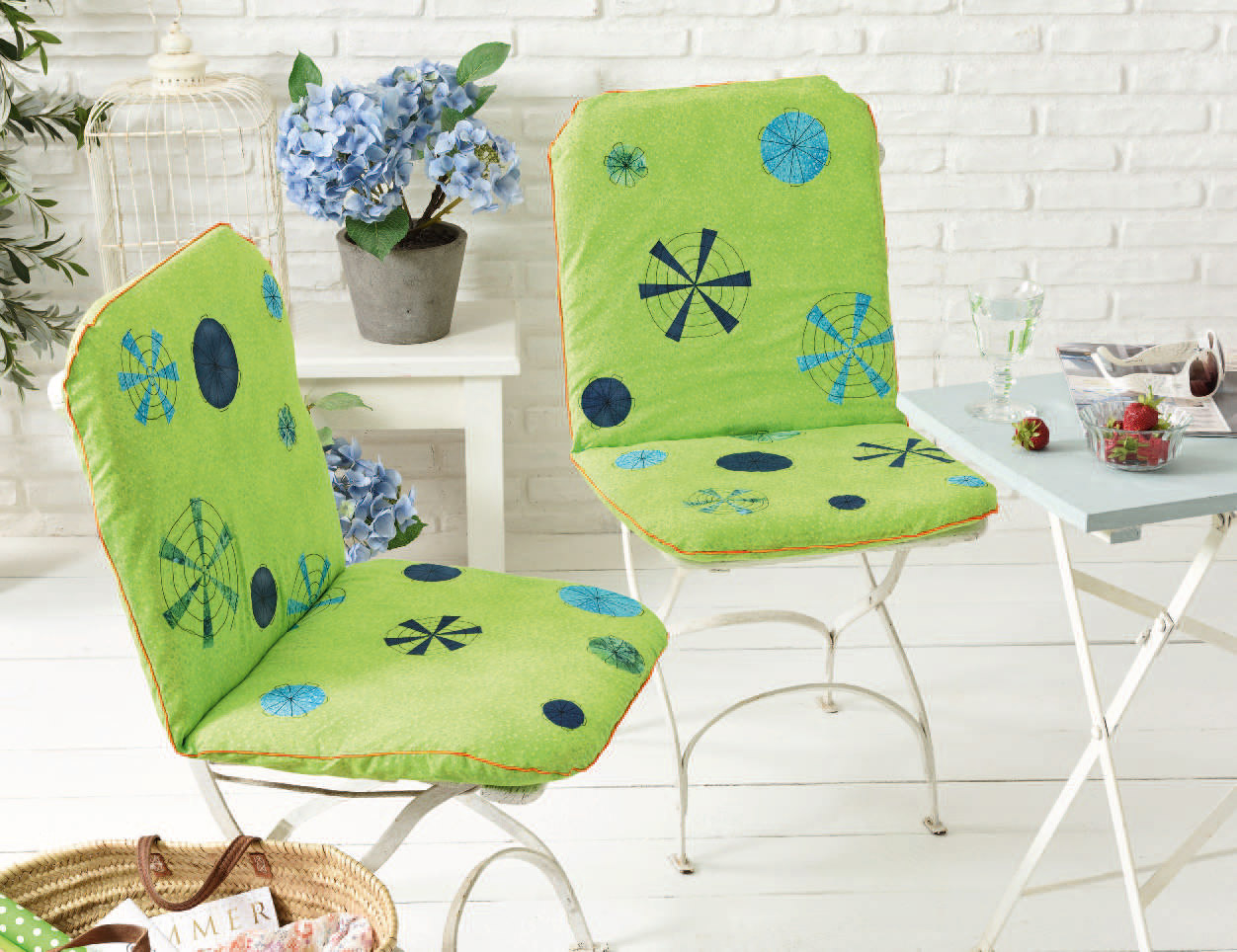 Leuchtend grüne Stuhlkissen mit blauen geometrischen Mustern, handgemacht, akzentuiert durch orangefarbene Kanten.
