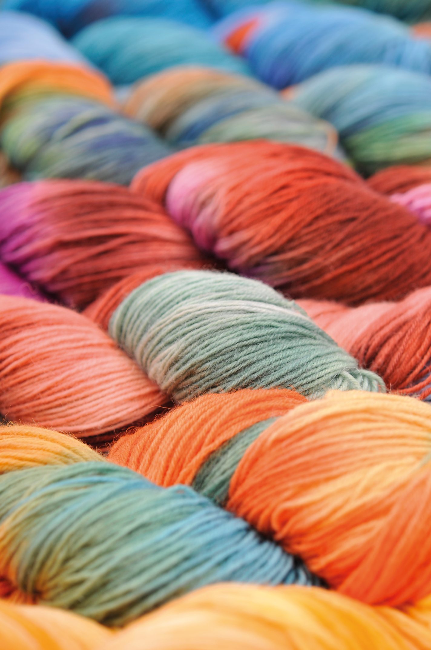 Bunte Garnstränge in lebhaften Farben. Ideal für handgemachte, kreative DIY Strick- und Häkelprojekte.