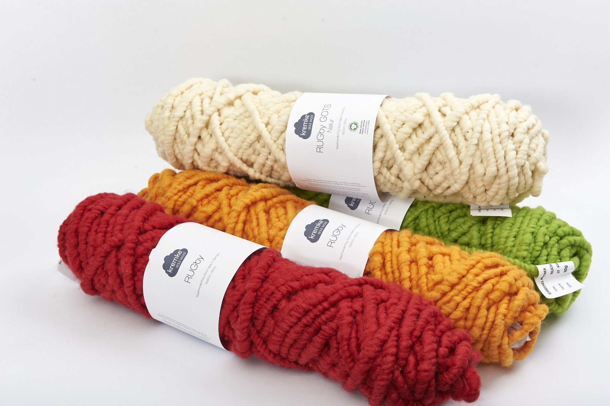 Kraftvoll gefärbte Wollrollen; Rot, Gelb, Grün, Creme. Perfekt für handgemachte Strickprojekte. DIY, modisch.