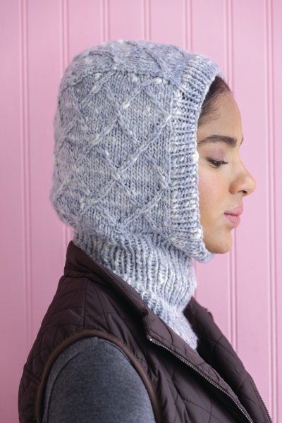 Selbstgemachte, graue gestrickte Kapuze mit Rautenmuster, kombiniert mit modischer Steppweste, warme Töne.