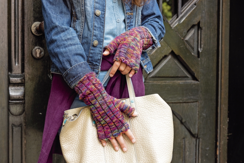 Jeansjacke, lila Strickhandschuhe, beiger Lederbeutel. Modisch, handgestrickt, trendig.
