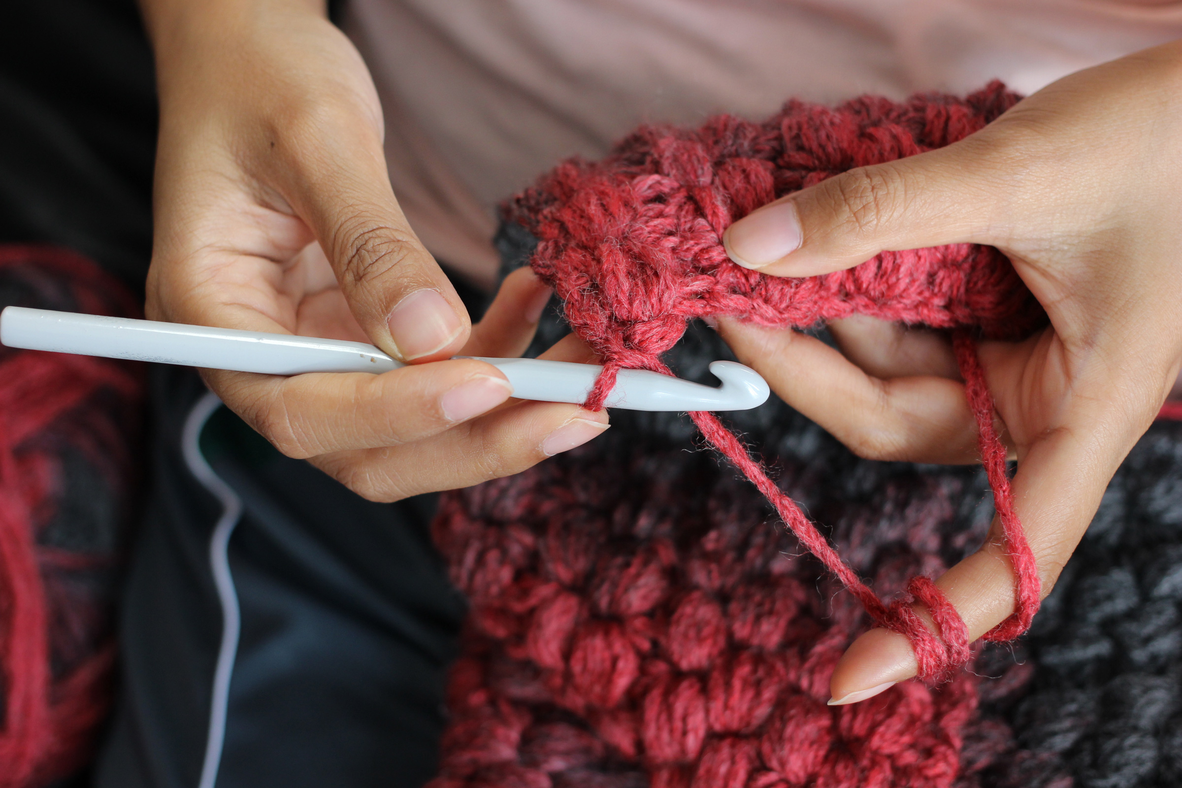 Selbstgemachtes Stück aus roter, flauschiger Wolle. DIY, handgemacht, modisch, kreatives Strickmuster.