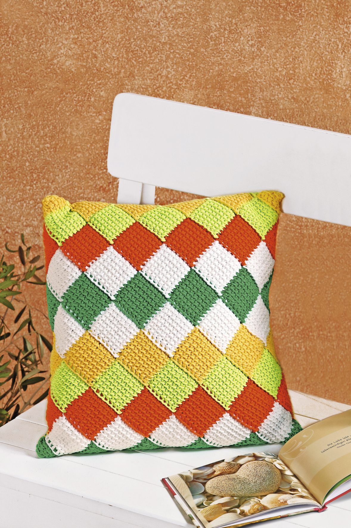 Handgemachtes Kissen, bunte Rautenmuster in Orange, Gelb, Grün und Weiß. DIY-Stil, lebendig und modisch.