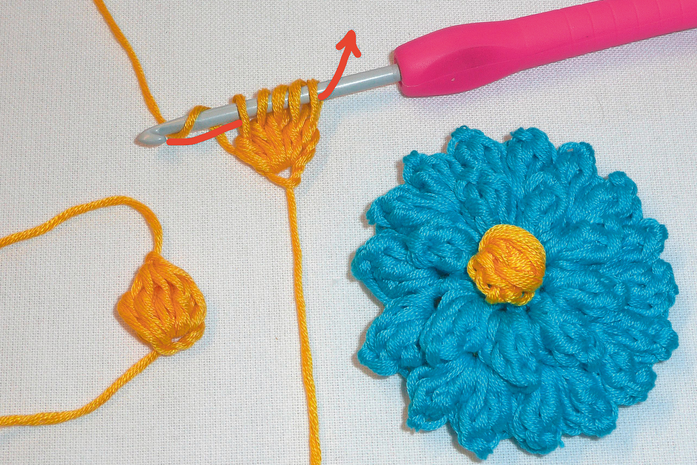 Handgefertigtes Blumenmuster in Blau und Gelb, gehäkelt. Modisch und kunsthandwerklich, DIY-Anspruch.