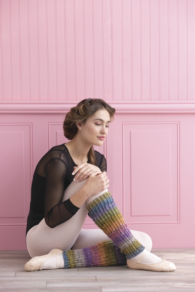 Modisches Outfit mit regenbogenfarbenen Stulpen, schwarzem Netz-Top und eleganten Ballettschuhen.
