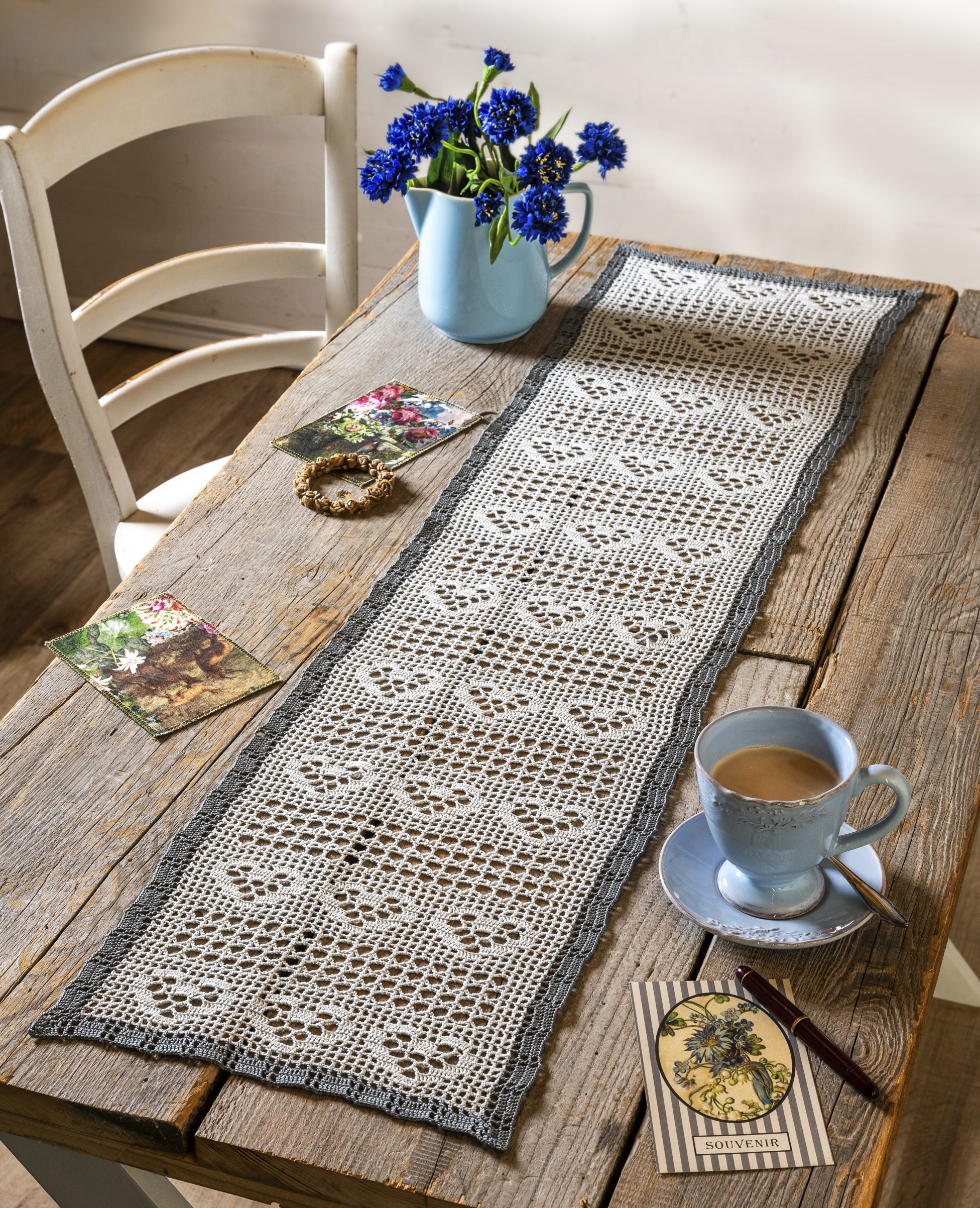 Beiger Häkel-Tischläufer mit grauem Rand; filigrane Muster, handgemacht, DIY-Stil, rustikal-elegant.