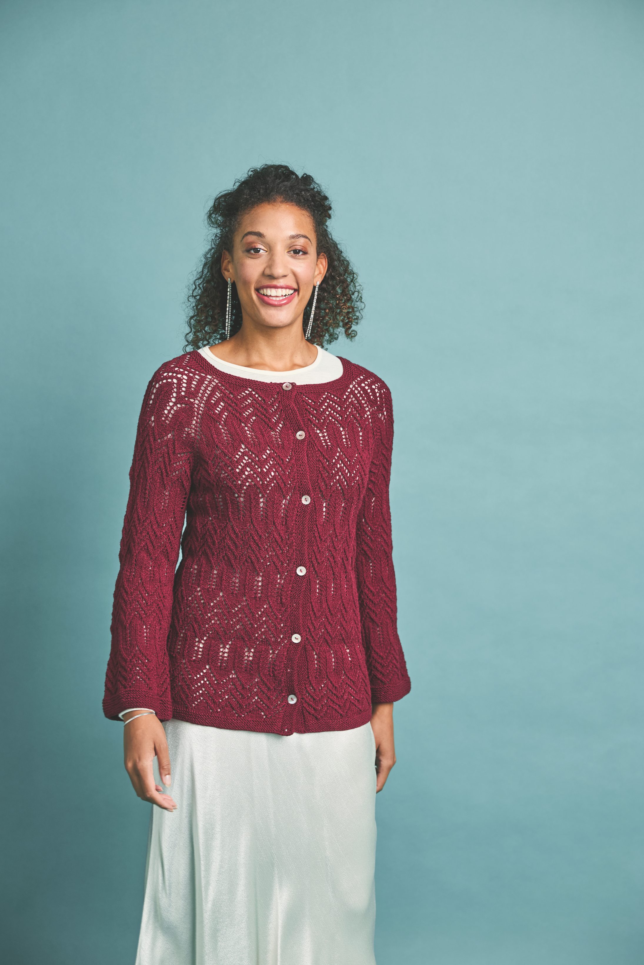 Burgunder Strickjacke mit Zopfmuster, handgemacht, kombiniert mit cremefarbenem, fließendem Rock. Modisch und elegant.